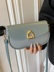 Elegant light blue crossbody bag with woven texture and gold horseshoe buckle detail