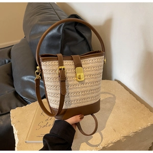 Detailed shot of woven bucket bag featuring brown leather trim and golden metal clasp