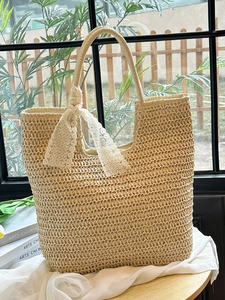 Handwoven straw tote bag with a white lace bow detail for a French vacation style