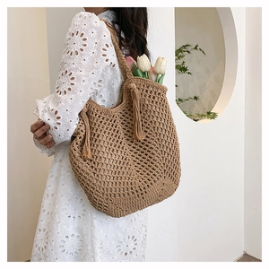 Detail of woven straw tote bag with long tassels and interior tulips on a white dress