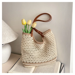 Close-up of bohemian woven tote bag with hollow crochet design and leather handles