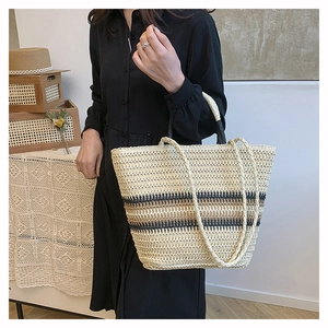 Detail of hand-woven straw tote bag with striped pattern and dual woven handles