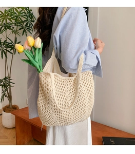 Close-up of cream white crochet knit tote bag with openwork mesh texture and soft strap