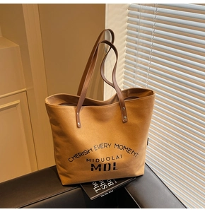 Detail of caramel canvas tote bag showing Chersih Every Moment print and leather strap