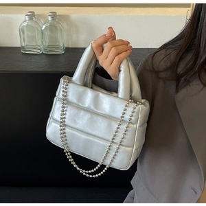 Close-up of metallic silver quilted bucket bag with chain strap and padded handle