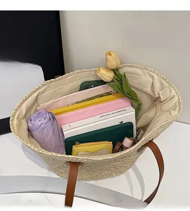 Macro view of a large straw tote bag showing a spacious interior for a phone and umbrella