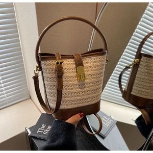 Detail view of the hand-woven straw bucket bag with dark brown leather trim and golden buckle