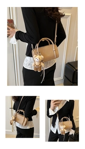 Detailed view of beige leather handbag with cute bear charm and adjustable shoulder strap