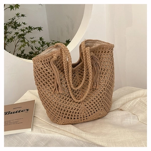 Close-up of woven tote bag with fringe details and soft fabric lining on white linen