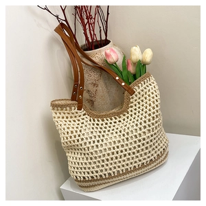 Detail of woven beach tote featuring beige mesh patterns and brown leather handles