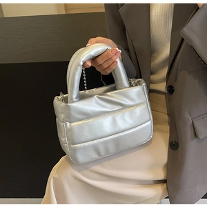 Silver quilted bucket bag with chain strap shown from a side view on a fashion model