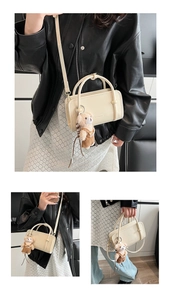 Detail view of cream-colored rectangular handbag with bear charm and adjustable strap