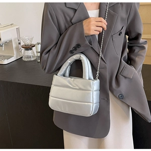 Chic silver quilted bucket bag with chain strap shown in a modern cafe setting