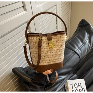 Detail of woven straw bucket bag with brown leather trim and golden metal clasp