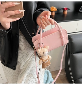 Detailed view of pink crossbody bag with cute plush bear pendant and thin shoulder strap
