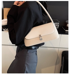 Détail du sac sous l'aisselle beige avec texture tissée et rabat en cuir lisse