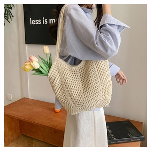 Detail of a beige hand-woven crochet tote bag with hollow mesh design in a home setting