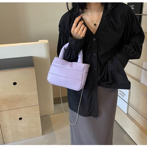 Detail of light purple quilted puffer bag with chain strap and matching padded handle