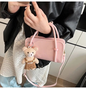 Detailed view of cream pink handbag with cute plush bear pendant and metal text detail