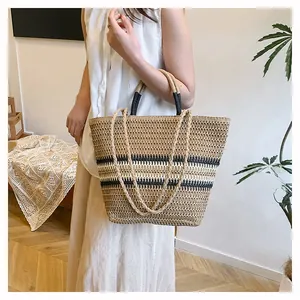 Detailed woven straw tote bag with black stripes and dual handle straps on a model
