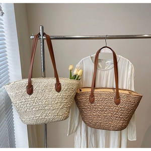 Detail of woven straw tote bags with brown leather straps in a summer resort setting