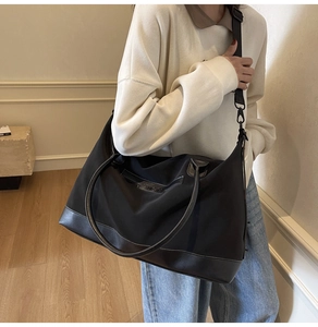 Close-up of large black nylon tote bag with leather logo patch and detachable shoulder strap