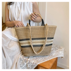 Detail of hand-woven straw tote bag with black stripes and circular handle