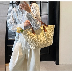 Detail of woven straw tote bag with brown leather handles and decorative tulips