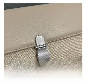 Détail macro du fermoir en métal argenté sur le sac à bandoulière en cuir kaki et beige