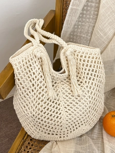 Bohemian crochet tote bag with tassels and cotton rope weaving on a rustic chair