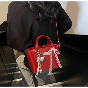 Detail of red wax leather bucket bag with silver bow charm and white lace bow decoration