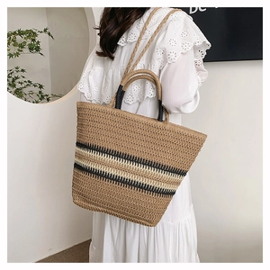 Detail of hand-woven straw tote bag with black and white stripes for travel and beach