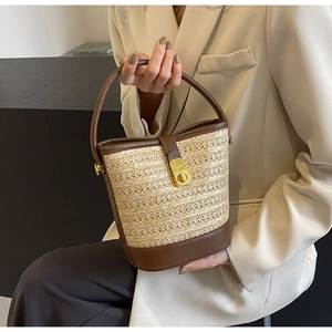 Detailed macro view of woven straw texture and premium brown leather bucket bag trim