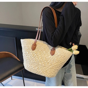 Close-up of large straw tote bag with brown leather handles and decorative tulips