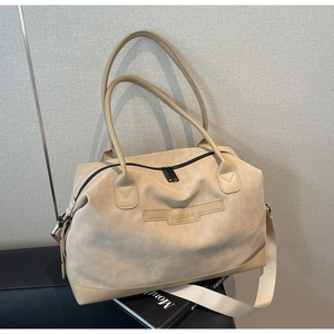 Detailed macro view of the beige tote bag featuring brand engraving and woven shoulder strap