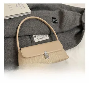 Détail du sac bandoulière beige à texture tissée avec boucle argentée sur manteau