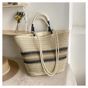 Close-up of woven straw tote bag with brown stripes and dual handles on a wooden shelf