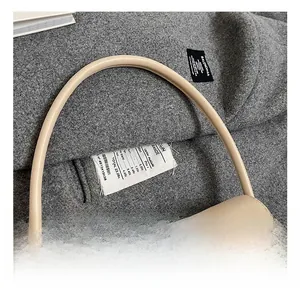 Détail d'un sac sous les bras en cuir beige minimaliste avec poignée ronde et fini mat