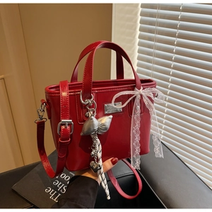 Detail of red oil wax leather bucket bag with lace bow and silver fashion lady tag