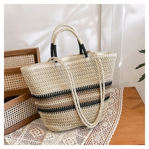 Close-up of woven straw tote bag with striped pattern and dual handles in soft light