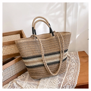 Macro detail of handwoven straw tote bag with black stripes and reinforced handles