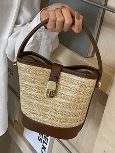 Minimalist straw bucket bag with brown leather trim and golden metal swivel lock