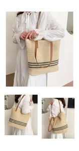 Detail of a woven straw tote bag with black stripes and brown leather shoulder straps