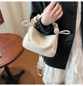 Detail view of cream white pleated pillow bag featuring soft PU leather and side drawstring