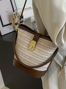 Minimalist straw bucket bag with brown leather trim and golden lock detail for women