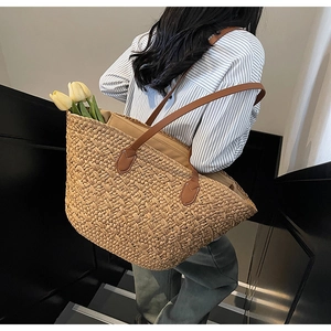 Close-up of large woven tote bag featuring straw texture and brown leather straps