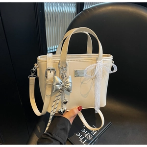 Detail of cream bucket bag showing silver heart charm and white lace bow decoration