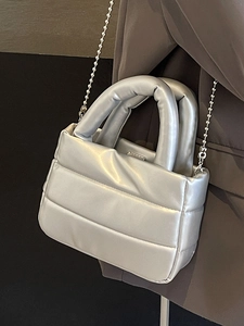 Silver quilted bucket bag with metallic finish and bead chain strap shown on a shoulder