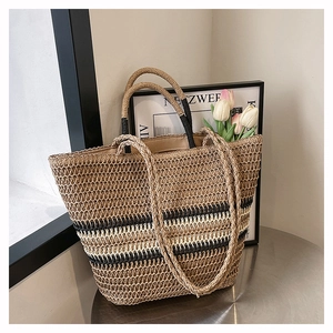 Detail showing handwoven straw texture and black-white stripes of the large tote bag