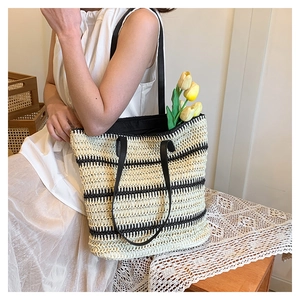Detail shot of a striped woven tote bag featuring black leather straps and tulip decor